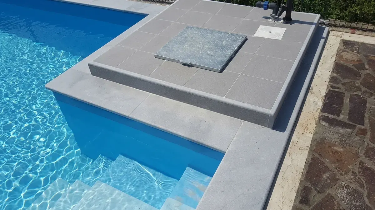 Kut bazena sa stepenicama i povišenim kamenim platoom od sivog kamena