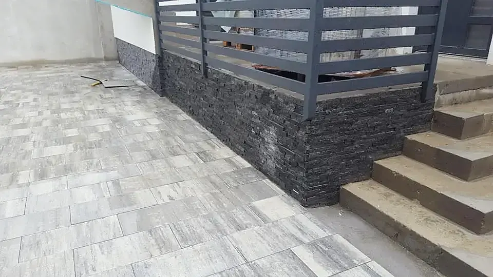 Tamna kamena obloga podnožja ograde uz kamene stube i popločenu terasu
