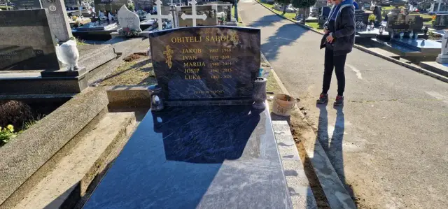 Tamni grob s poliranom pokrovnom pločom i lampionom uz rub staze