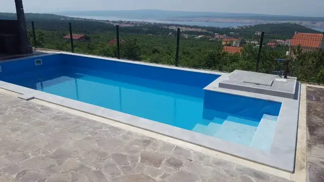 Pravokutni bazen sa sivim kamenim rubom na terasi s pogledom na more