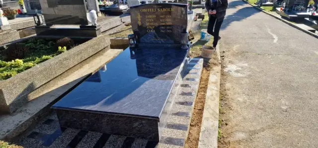 Tamni granitni grob okružen opločenjem od svijetlih i tamnih traka