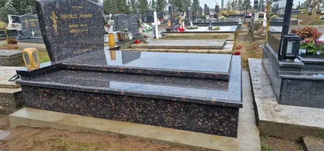Široki smeđi granitni grob s dvostrukim rubom uz susjedni sivi spomenik