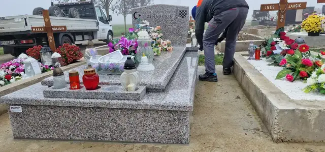 Svijetlosivi granitni grob ukrašen cvijećem i crvenim lampionima na groblju