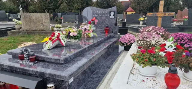 Sivi prošarani grob s cvjetnim aranžmanima i crvenim lampionima