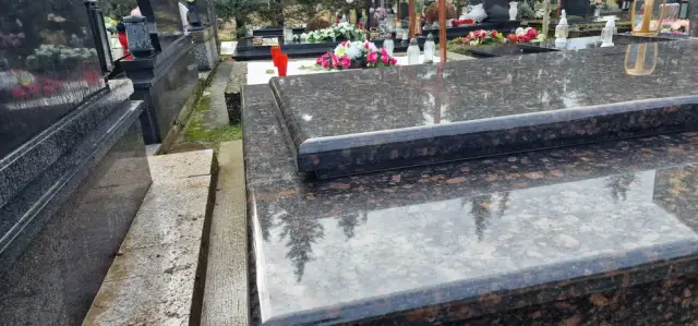 Krupni plan poliranih smeđih granitnih ploča i stepenastog ruba groba