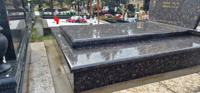 Bočna strana smeđeg granitnog groba s izdignutom pločom među spomenicima