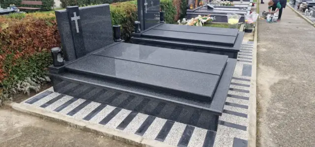 Dva susjedna tamna dvojna groba uz prugasto opločenje i grobljansku stazu