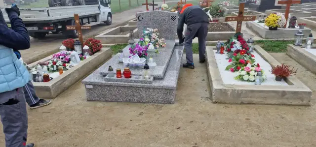 Svijetlosivi grob s cvijećem i lampionima tijekom radova na groblju