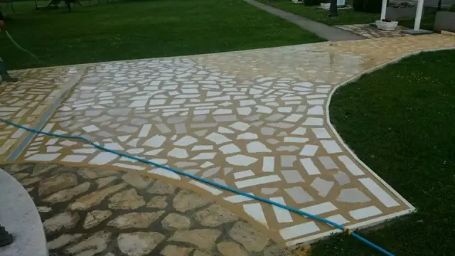 Vrtna staza od nepravilnih svijetlih kamenih ploča između zelenih travnjaka