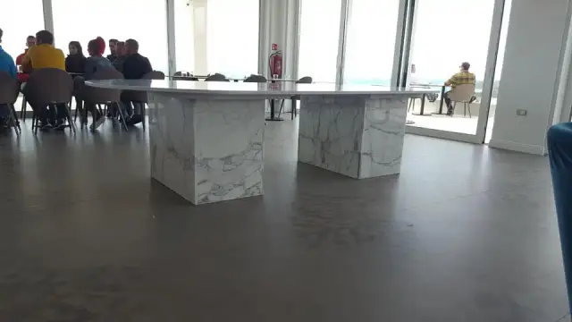 Bočni pogled na bijeli stol s dvjema kamenim nogama uz prozore