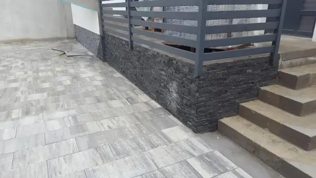 Tamnosiva kamena obloga podnožja ograde uz vanjske stube i popločenu stazu