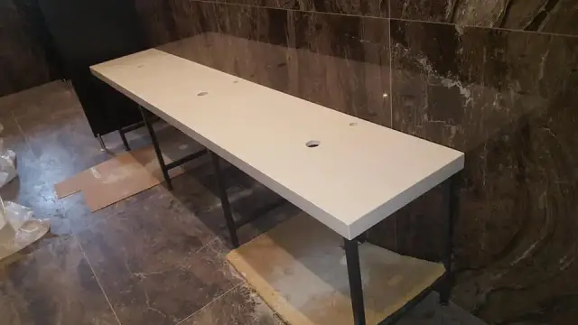 Duga bijela ploča za umivaonike s otvorima uz smeđu kamenu oblogu