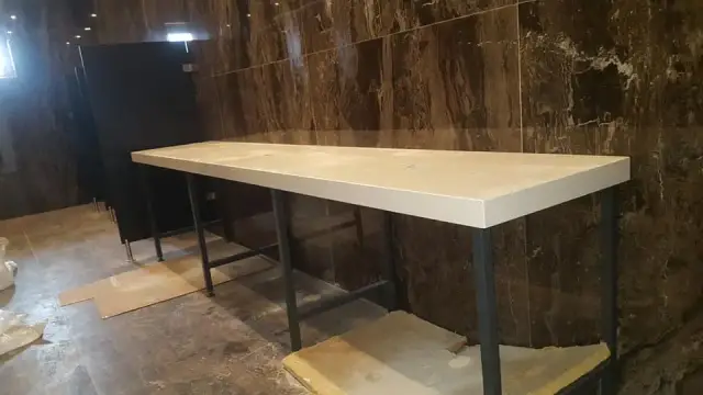 Bijela kamena ploča za umivaonike na metalnim nosačima u kupaonici
