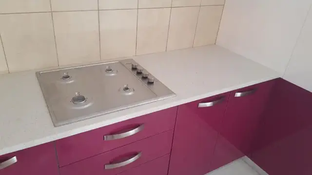 Svijetla kamena kuhinjska ploča s plinskim kuhalom iznad ljubičastih ladica