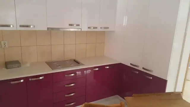 Svijetla kutna radna ploča u kuhinji s ljubičastim donjim ormarićima