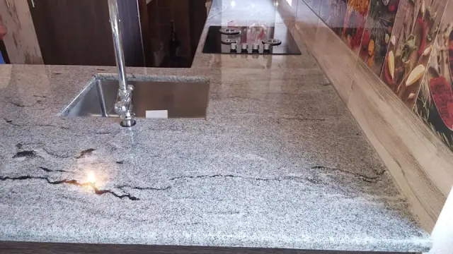 Siva prošarana granitna ploča sa sudoperom i kuhalom u kuhinji