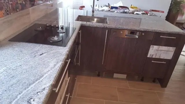Kutna siva granitna ploča s crnim kuhalom na drvenim kuhinjskim elementima