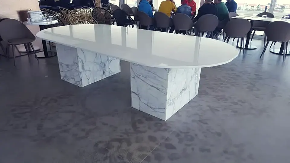 Dugi bijeli ovalni stol na dvama postoljima od prošaranog mramora